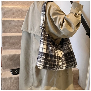 Detail of a large black and white checkered fuzzy tote bag on a modern staircase