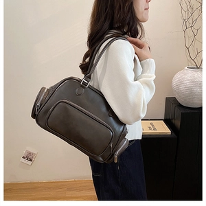 Detail of large brown leather tote bag with silver zippers and side pockets on model