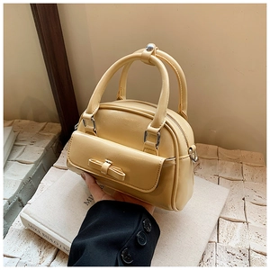Detail of a creamy yellow Boston bag featuring a stylish bow pocket and silver hardware