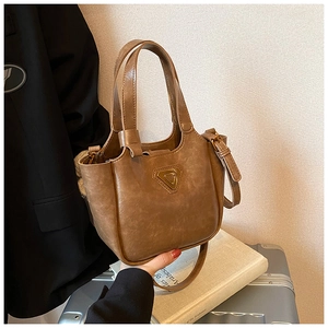 Close-up of vintage brown leather bucket bag with metallic logo and adjustable strap