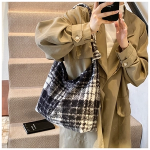 Detail of black and white checkered fuzzy tote bag featuring an integrated knot shoulder strap