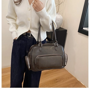 Detail of dark brown faux leather bag with functional side pockets and metallic zippers
