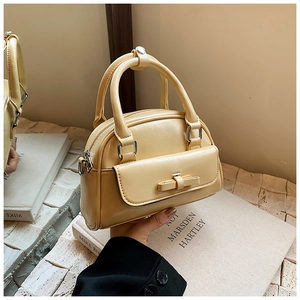 Close-up of beige Boston bag with bow detail and textured PU leather on aesthetic background