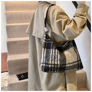 Detail shot of a plush black and white checkered tote bag on a model in a trench coat