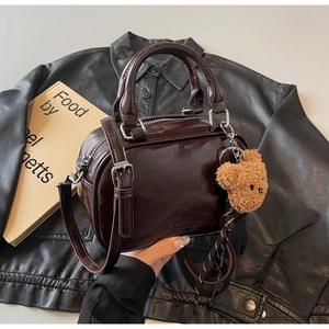 Détail du sac en cuir verni marron foncé avec pendentif ours en peluche et fermeture