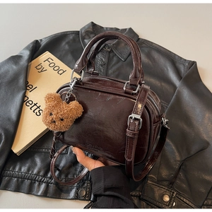 Détail d'un sac bowling en cuir marron foncé avec finitions argentées et charm ours