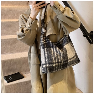 Close-up of black and white plaid plush tote bag texture with thick shoulder strap