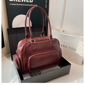 Detail shot of a vintage burgundy bowling bag with silver zippers in a gift box
