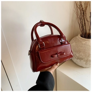 Detail of wine red glossy Boston bag with a sweet bow knot and sturdy dual handles