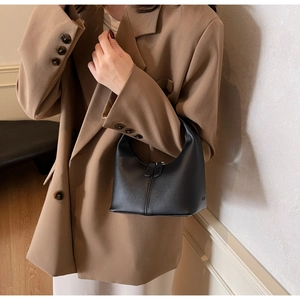 Chic black leather hobo bag with vertical stitching shown on model in neutral outfit