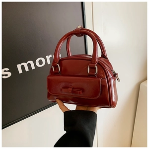 Detailed shot of a burgundy patent leather Boston bag with a sweet bow decoration