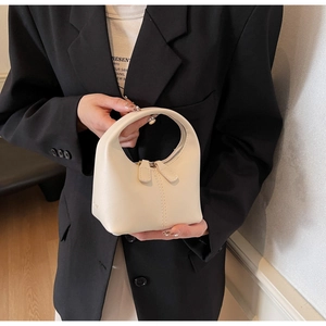 Detailed view of a cream leather crescent handbag with a sleek integrated handle
