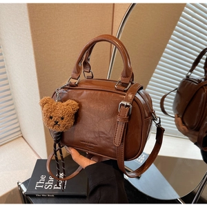 Détail de la texture cuir PU marron ciré et des éléments métalliques argentés du sac