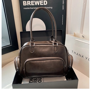 Detail of a large brown faux leather hobo bag with zip pockets and silver hardware