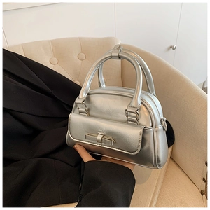Detailed close-up of silver metallic Boston bag with bow pocket and sturdy dual handles