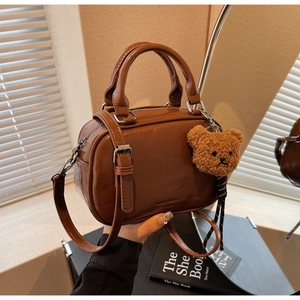 Gros plan du sac bowling marron verni avec pendentif ours en peluche mignon