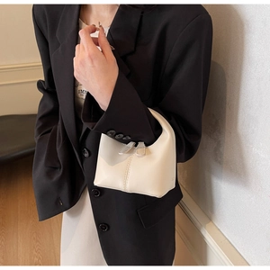 Detail of cream white leather handbag with double zippers on a black blazer outfit