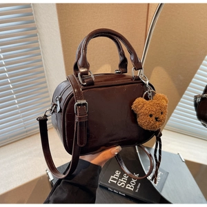 Détail du sac bowling marron vintage avec zip argenté et charm ours en peluche
