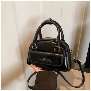 Detail of a black glossy Boston bag featuring a bow pocket and silver hardware accents