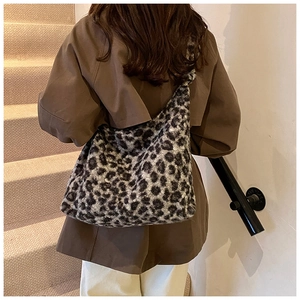 Leopard print plush tote bag shown on a model in a warm indoor staircase setting