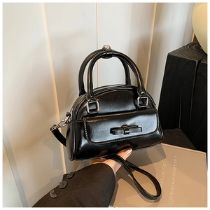 Close-up of black Boston bag featuring a bow pocket, silver hardware, and double handles