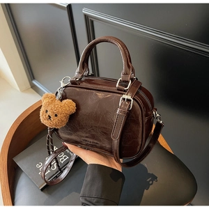 Détail du sac en cuir huilé marron foncé avec texture luxueuse et breloque ourson