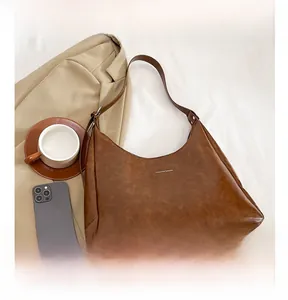 Detail view of brown PU leather hobo bag with Fashion & Bags text on a casual bed setting