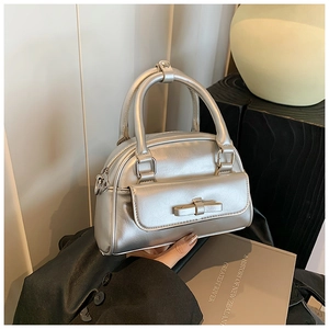 Detailed macro view of a silver metallic Boston bag featuring a stylish bow pocket detail