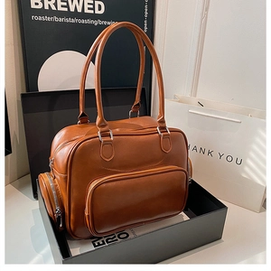 Detailed shot of brown PU leather Boston shoulder bag with side zip pocket in a gift box