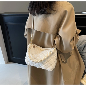 Sac bandoulière matelassé en peluche blanche avec poignée tressée porté par un mannequin