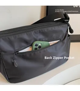 Détail de la poche zippée antivol au dos de ce grand sac à bandoulière en nylon noir