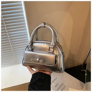 Detailed view of silver metallic bow bag with front pocket and sturdy top handles
