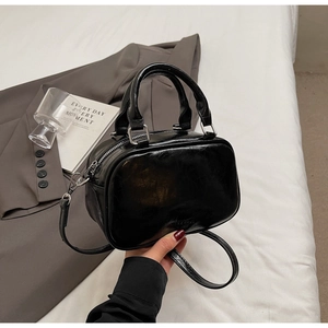 Détail du mini sac Boston en cuir brillant noir avec quincaillerie argentée et anses
