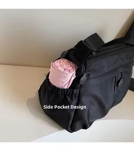 Détail de la poche latérale sur un sac en nylon noir avec un parapluie rose plié
