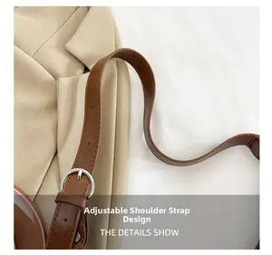 Detail of adjustable brown leather shoulder strap with silver buckle on a beige blazer