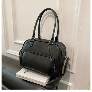 Macro view of a black Boston bag with dual handles and side circular pockets