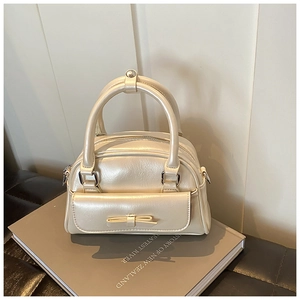 Close-up of creamy white Boston bag with elegant bow detail and glossy leather texture