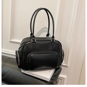 Detailed view of black leather shoulder bag with silver zippers on a vintage sofa