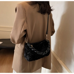 Détail du sac à bandoulière en fausse fourrure noire avec poignée tressée et détails dorés