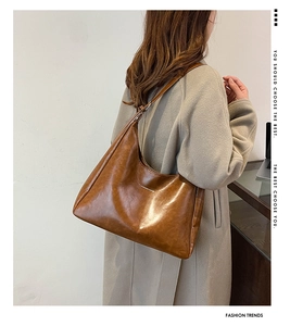 Brown vintage leather hobo bag with Fashion & Bags lettering shown on a beige coat