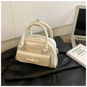 Macro shot of cream Boston bag with bow detail and textured synthetic leather