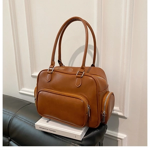 Detail of a brown leather shoulder bag with side zipper pockets and smooth texture