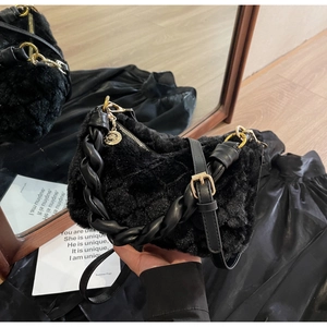 Détail du sac en peluche noir avec poignée en cuir torsadée et finitions dorées