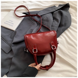 Detail of dark red Boston bag in polished leather with silver hardware and top handle