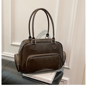 Detail of dark brown vintage faux leather tote bag with silver zippers on a black sofa