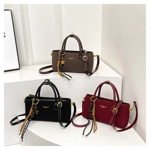 Detailed view of hand-held crossbody bags in black, dark brown, and wine red colors