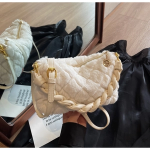 Détail du sac matelassé en peluche blanche avec dorures et poignée tressée