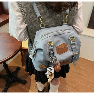 Detail of light blue denim backpack with cute bear pendant and leather brand tag