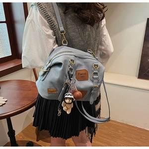 Detail of light blue denim hobo bag featuring cute bear charm and leather brand patches