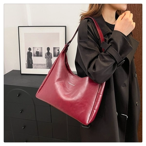 Close-up of burgundy hobo bag with Fashion & Bags logo worn with a black trench coat